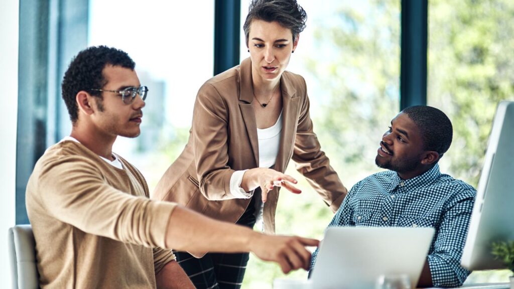 A team of marketing employees working together over a laptop.